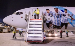Members of the Argentinian team peer out from the windows of their plane adorned with a picture of Lionel Messi and team-mates as they arrive at the Hamad International Airport in Doha on November 17: AFP/Odd Andersen