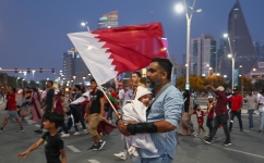 A man carrying a Qatar flag holds his baby as he arrives at the FIFA Fan Festival in Doha’s Al Bidda Park: AFP/Fabrice Coffrini