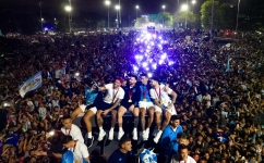 Argentina's captain Lionel Messi (centre) holds the FIFA World Cup Trophy on board a bus as he celebrates alongside teammates and in Ezeiza, Buenos Aires province, Argentina on December 20, 2022. (Photo by Tomas CUESTA / AFP)