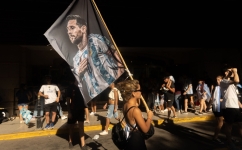 A fan of Argentina holds a flag with an image of Argentine forward Lionel Messi as she celebrates winning the Qatar 2022 World Cup at 9 de Julio avenue in Buenos Aires, on December 18, 2022. (Photo by TOMAS CUESTA / AFP)