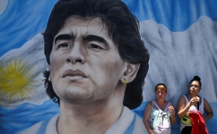 Members of social organizations stand next to a mural depicting late Argentine football star Diego Maradona during a protest at Pueyrredon bridge in Buenos Aires on December 2, 2022. (Photo by Luis ROBAYO / AFP)