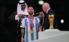 The Amir His Highness Sheikh Tamim bin Hamad Al Thani wraps the cloak around Lionel Messi as FIFA chief Gianni Infantino watches on: AFP/Paul Ellis