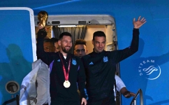 Argentina captain Lionel Messi holds the FIFA World Cup trophy alongside coach Lionel Scaloni as they step off a plane upon arrival in Ezeiza, Buenos Aires: AFP/Luis Robayo