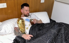 In this handout picture, Lionel Messi sips mate in bed while holding the FIFA World Cup Trophy at the AFA training centre in Ezeiza, Argentina, on December 20, 2022. (Photo by INSTAGRAM ACCOUNT OF @leomessi / AFP)