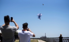 People take pictures with their cell phones of a helicopter carrying a giant t-shirt of Argentine forward Lionel Messi over Rosario, Argentina, on December 13, 2022. (Photo by AFP)