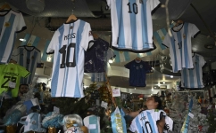 :A woman organizes t-shirts of the Argentine national football team inside a store in the eve of the Qatar 2022 World Cup final match between Argentina and France in Buenos Aires, on December 16, 2022. (Photo by Luis ROBAYO / AFP)