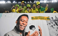 Brazil fans cheer in the stands above a banner depicting superstar Pele ahead of the Qatar 2022 World Cup round of 16 match between Brazil and South Korea at Stadium 974 in Doha on December 5, 2022. (Photo by NELSON ALMEIDA / AFP)