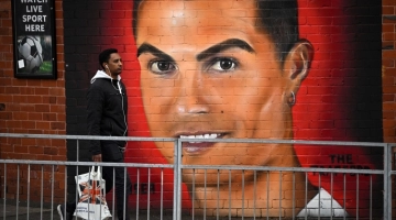 A pedestrian walks past a mural of Manchester United's Cristiano Ronaldo, near Old Trafford stadium, home ground of Manchester United football team in Manchester on November 23, 2022.   (Photo by Oli SCARFF / AFP)
