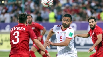 Iran's Omid Ebrahimi (C) fights for the ball with Syria's Mouaiad Alajman (L) during the friendly soccer match between Iran and Syria national teams at the Azadi Stadium in Tehran on June 6, 2019. / AFP / str