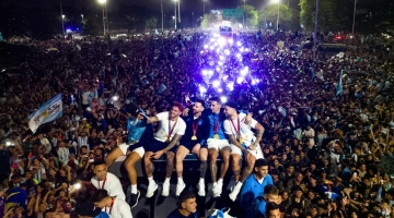 Argentina's captain Lionel Messi (centre) holds the FIFA World Cup Trophy on board a bus as he celebrates alongside teammates and in Ezeiza, Buenos Aires province, Argentina on December 20, 2022. (Photo by Tomas CUESTA / AFP)