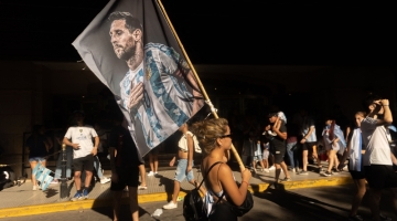 A fan of Argentina holds a flag with an image of Argentine forward Lionel Messi as she celebrates winning the Qatar 2022 World Cup at 9 de Julio avenue in Buenos Aires, on December 18, 2022. (Photo by TOMAS CUESTA / AFP)