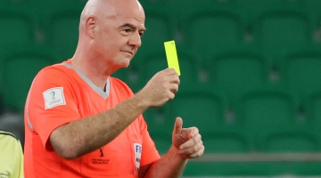 FIFA President Gianni Infantino wearing a referee uniform shows a yellow card as he officiates the friendly match of FIFA Legends and Qatar-based workers at Al Thumama Stadium in Doha on December 12, 2022. (Photo by KARIM JAAFAR / AFP)