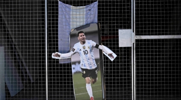 A poster with the image of Argentine football star Lionel Messi is seen in the gate of a store prior of the Qatar 2022 World Cup final football match between Argentina and France in Buenos Aires, on December 16, 2022. (Photo by Luis ROBAYO / AFP)