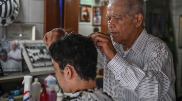 Barber Joao Araujo, known as Didi, who cut Brazilian football legend Pele's hair, works in his hairdressing salon in Santos, Brazil, on December 30, 2022.  (Photo by Nelson ALMEIDA / AFP)