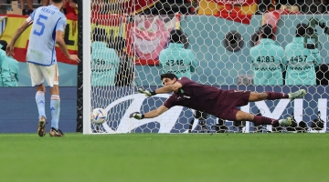 Morocco's goalkeeper Yassine Bounou saves a penalty from Spain's Sergio Busquets during the penalty shoot-out of their World Cup round of 16 match at the Education City Stadium in Al-Rayyan on December 6, 2022. (Photo by KARIM JAAFAR / AFP)