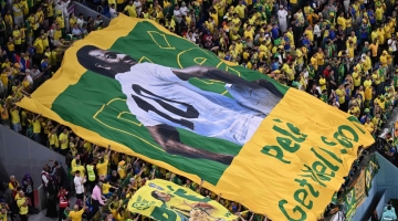 Fans hold a banner a banner depicting superstar Pele during the Qatar 2022 World Cup round of 16 match between Brazil and South Korea at Stadium 974 in Doha on December 5, 2022. (Photo by Kirill KUDRYAVTSEV / AFP)