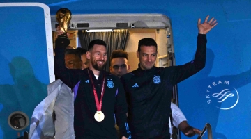 Argentina captain Lionel Messi holds the FIFA World Cup trophy alongside coach Lionel Scaloni as they step off a plane upon arrival in Ezeiza, Buenos Aires: AFP/Luis Robayo