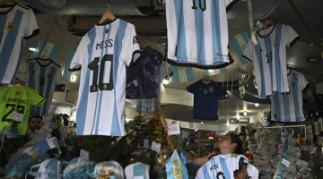 :A woman organizes t-shirts of the Argentine national football team inside a store in the eve of the Qatar 2022 World Cup final match between Argentina and France in Buenos Aires, on December 16, 2022. (Photo by Luis ROBAYO / AFP)