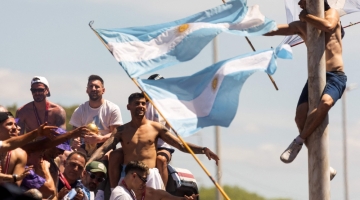 A fan of Argentina clinging to a pole cheers as the team parades on board a bus after winning the Qatar 2022 World Cup tournament, in Buenos Aires province, on December 20, 2022.  (Photo by TOMAS CUESTA / AFP)