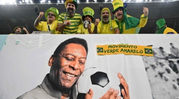 Brazil fans cheer in the stands above a banner depicting superstar Pele ahead of the Qatar 2022 World Cup round of 16 match between Brazil and South Korea at Stadium 974 in Doha on December 5, 2022. (Photo by NELSON ALMEIDA / AFP)
