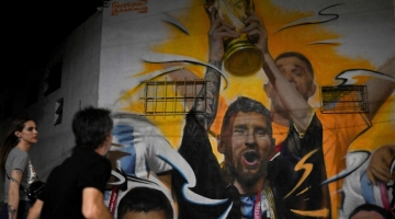 A mural by artist Maxi Bagnasco depicting Argentina's captain Lionel Messi raising trophy next to his teammates after winning the Qatar 2022 World Cup tournament is seen in Buenos Aires on December 22, 2022. (Photo by Luis ROBAYO / AFP)