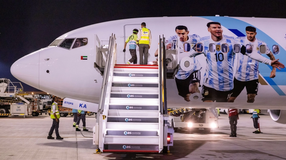 Members of the Argentinian team peer out from the windows of their plane adorned with a picture of Lionel Messi and team-mates as they arrive at the Hamad International Airport in Doha on November 17: AFP/Odd Andersen