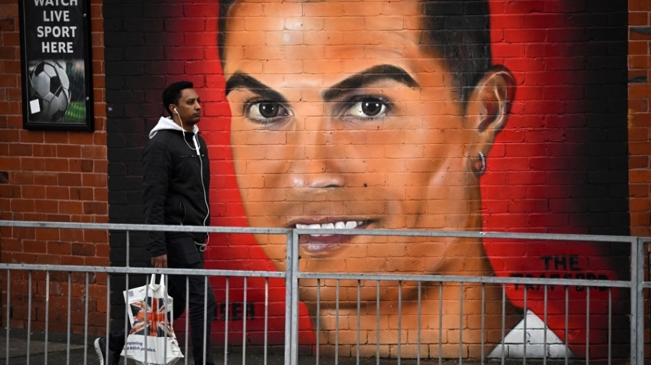 A pedestrian walks past a mural of Manchester United's Cristiano Ronaldo, near Old Trafford stadium, home ground of Manchester United football team in Manchester on November 23, 2022.   (Photo by Oli SCARFF / AFP)