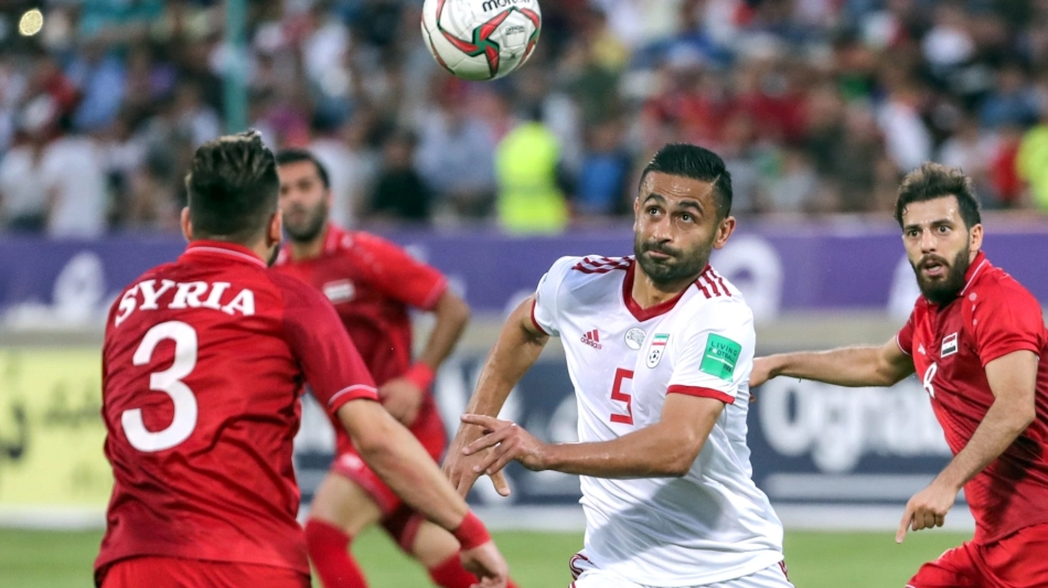 Iran's Omid Ebrahimi (C) fights for the ball with Syria's Mouaiad Alajman (L) during the friendly soccer match between Iran and Syria national teams at the Azadi Stadium in Tehran on June 6, 2019. / AFP / str