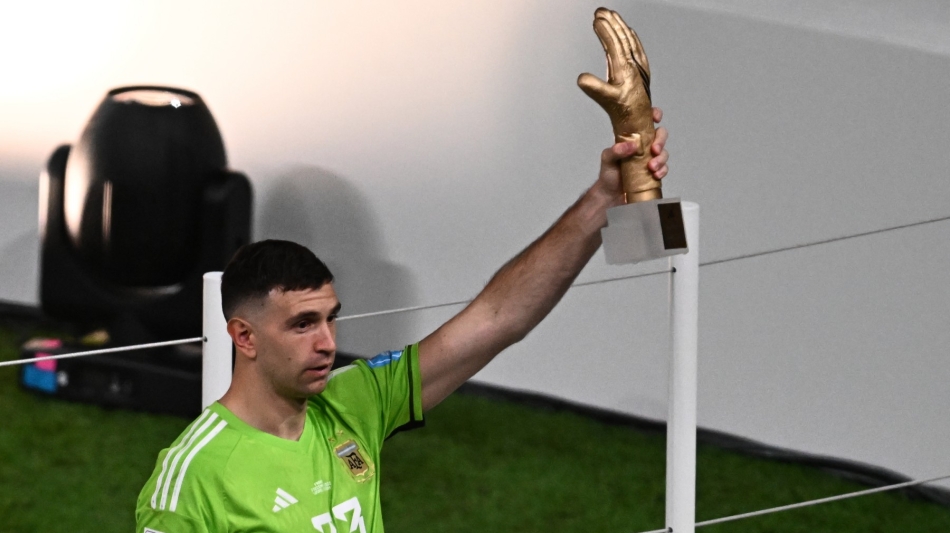 Argentina's goalkeeper Emiliano Martinez poses for pictures holding the Golden Glove award trophy at the end of the Qatar 2022 World Cup final at Lusail Stadium in Lusailon December 18, 2022. (Photo by Jewel SAMAD / AFP)