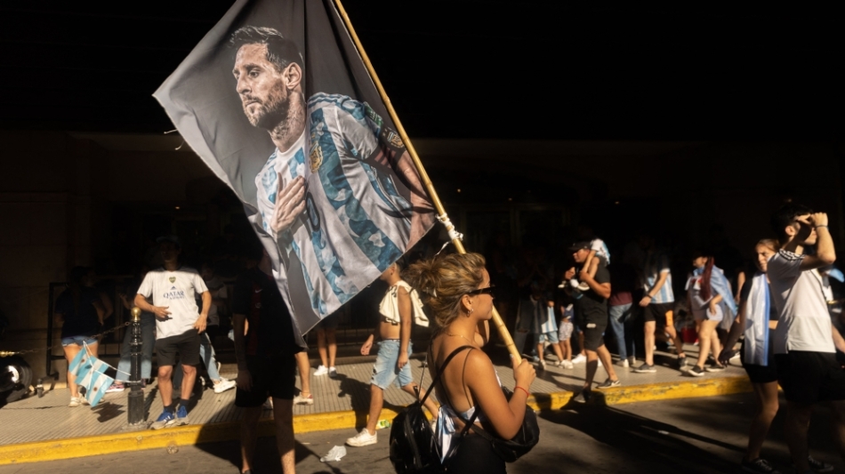 A fan of Argentina holds a flag with an image of Argentine forward Lionel Messi as she celebrates winning the Qatar 2022 World Cup at 9 de Julio avenue in Buenos Aires, on December 18, 2022. (Photo by TOMAS CUESTA / AFP)