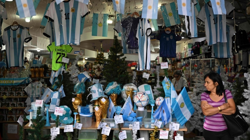 A woman walks inside a store in the eve of the Qatar 2022 World Cup final match between Argentina and France in Buenos Aires, on December 16, 2022. (Photo by Luis ROBAYO / AFP)