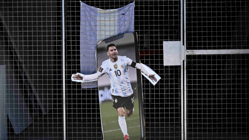 A poster with the image of Argentine football star Lionel Messi is seen in the gate of a store prior of the Qatar 2022 World Cup final football match between Argentina and France in Buenos Aires, on December 16, 2022. (Photo by Luis ROBAYO / AFP)