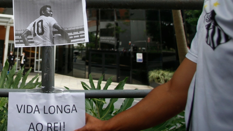 Fans place a picture of Brazilian legend Pele and a sign reading 'Long Life to the King!" outside the hospital entrance, where he is hospitalised in Sao Paulo, Brazil, on December 4, 2022. (Photo by Miguel Schincariol / AFP)