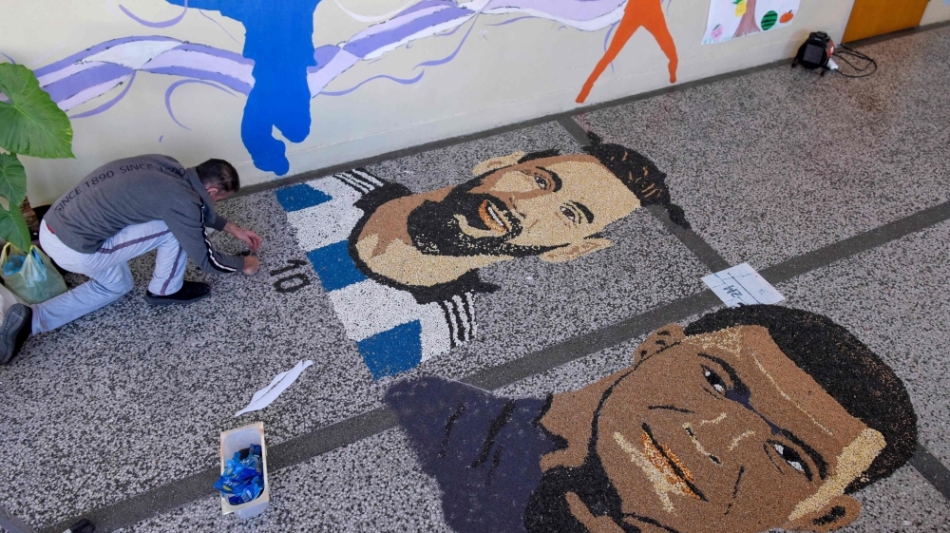 Kosovar artist Alkent Pozhegu works on the last details of his mosaic, made with grain and seeds, depicting Lionel Messi and Kylian Mbappe in Gjakova on December 17, 2022. (Photo by Armend NIMANI / AFP)
