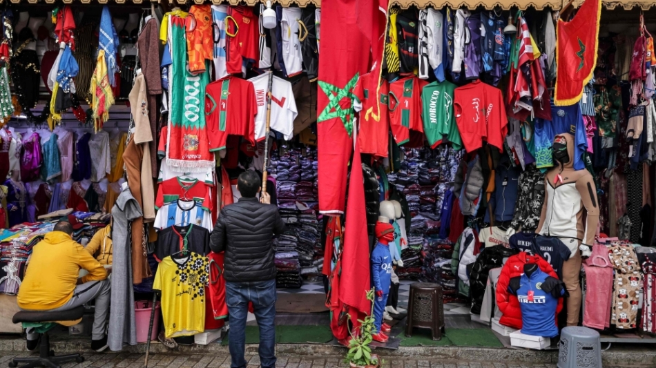 A shop keeper hangs a football jersey at a sports apparel shop in Morocco's capital Rabat on December 13, 2022 a day ahead of the FIFA World Cup semi-final match between Morocco and France. (Photo by FADEL SENNA / AFP)