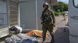 جندي إسرائيلي يقف إلى جوار جثث لإسرائيليين آخرين